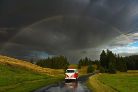 VW Bulli Erwin auf einer Landstraße unter einem Regenbogen